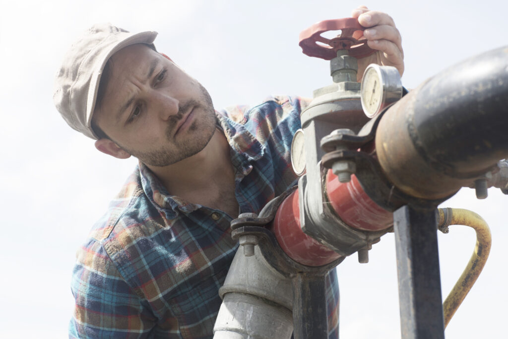 Technician inspecting an outdoor backflow preventer for signs of wear and compliance.